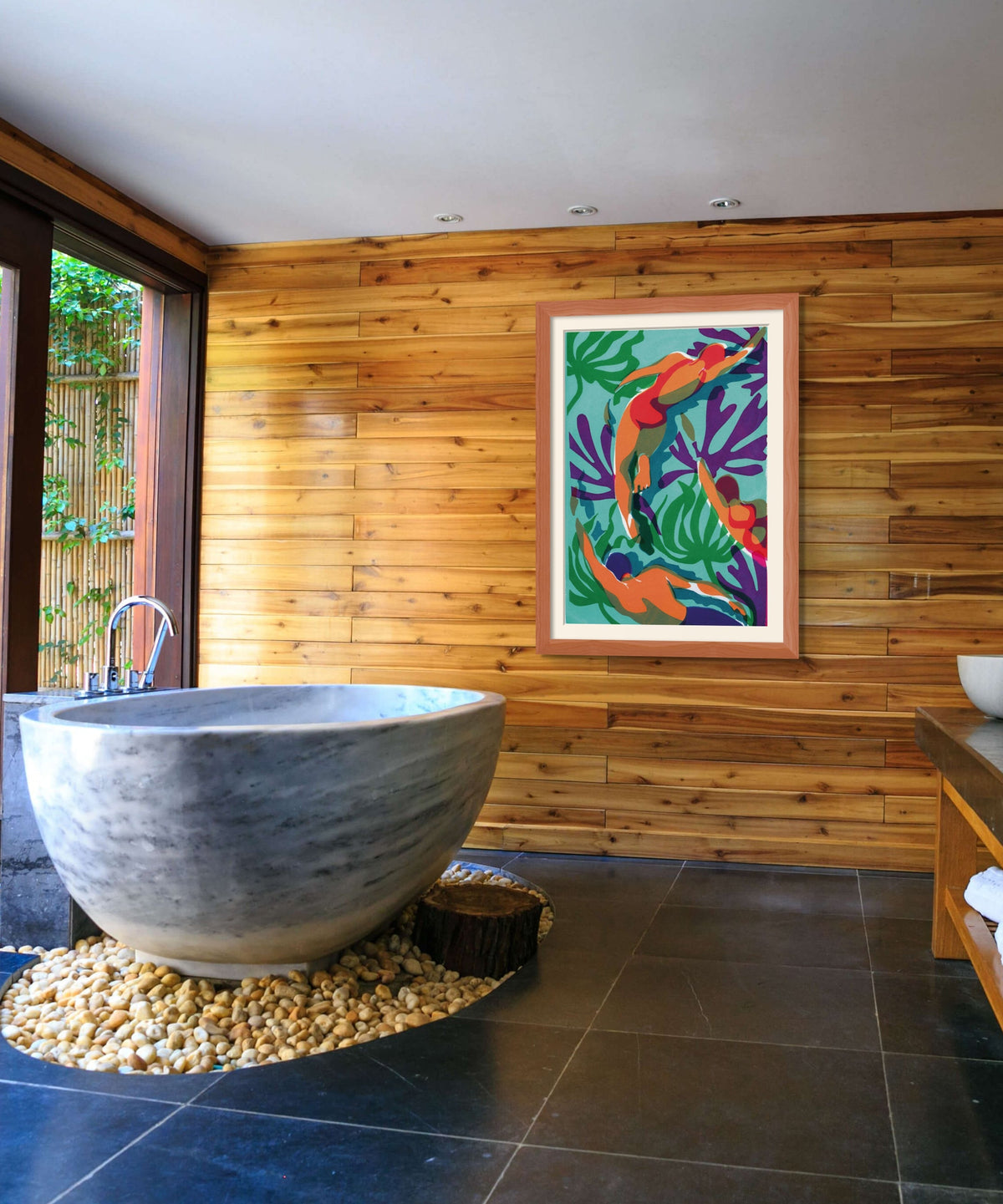 Marble-like grey stone sink in a wooden bathroom, framed colourful artwork, pebbled surround and large window to the left. Wild swimming Cornwall style spa vibe.